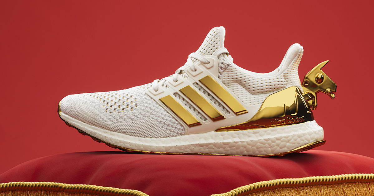 Adidas UltraBoost Victory Crown set fra siden med hvid og guld design